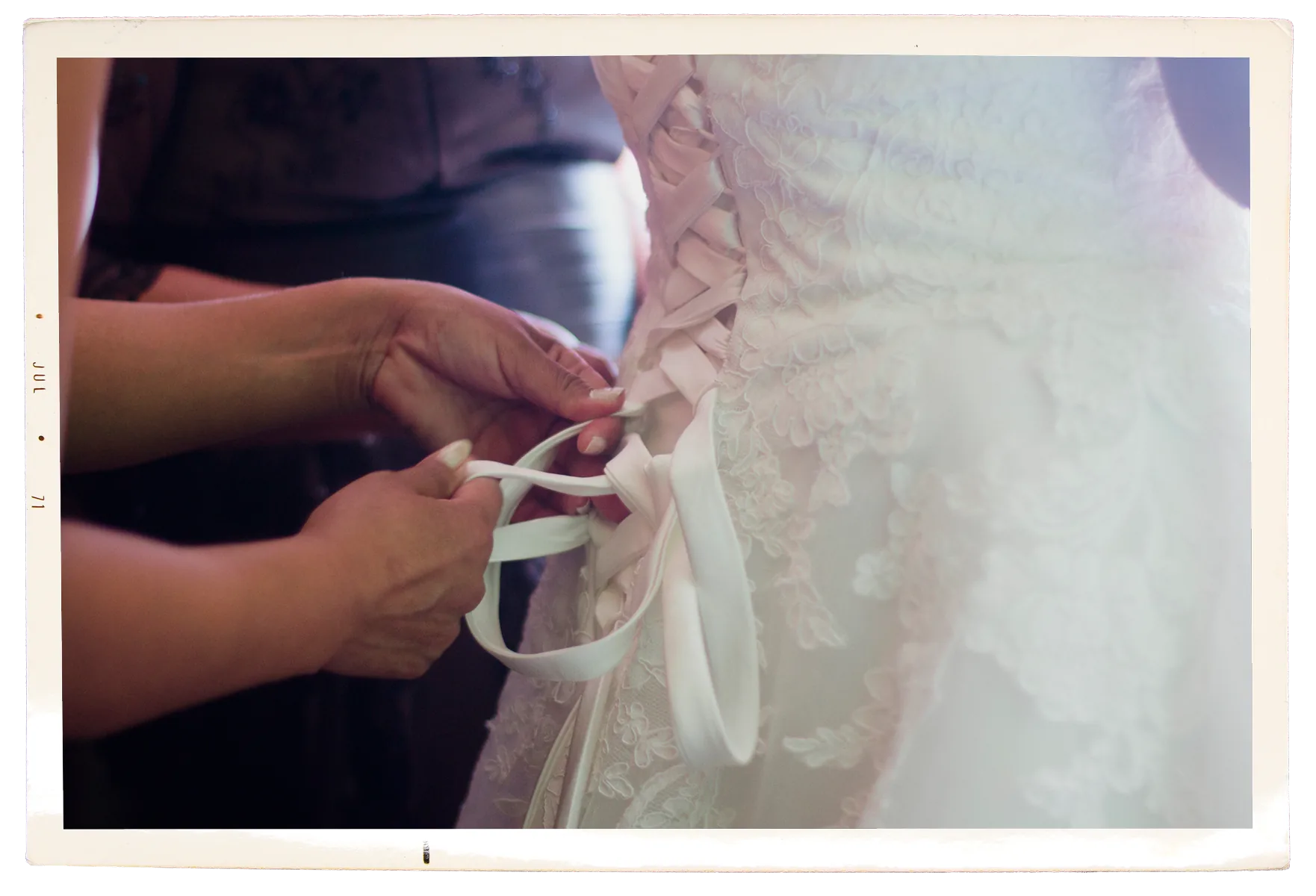 Manos atando el listón trasero del vestido de la novia
